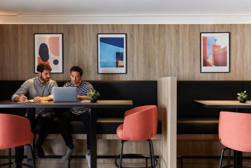 two men sitting at a table with a laptop at Crowne Plaza Hamburg-City Alster by IHG in Hamburg