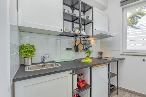 a kitchen with white cabinets and a sink at Maximilian&Stela in Poreč