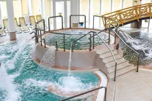 a water slide in a building with a waterfall at Hotel Kamilla in Balmazújváros