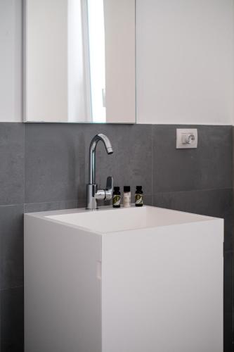 a white kitchen with a sink and a mirror at HelloAPULIA - Design Trulli Sampaolo with private pool - heated on request - Pet Friendly in Gioia del Colle