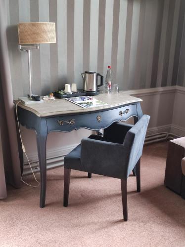 a blue desk with a chair and a lamp at Golf Hotel in Saint-Saëns