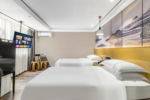 広州市にあるShangyuanHotel Quzhuang Branchのベッド2台とテレビがあるホテルの部屋
