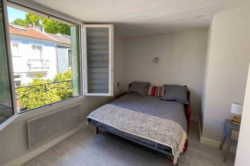 a small bedroom with a bed and a large window at Charming townhouse with garden in the City of Love in Paris