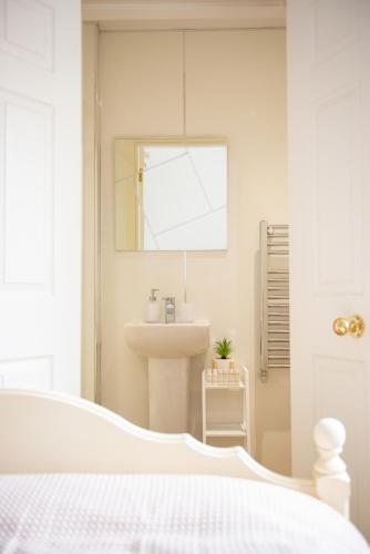 a white bedroom with a sink and a mirror at Parade School Guest Rooms in Berwick-Upon-Tweed