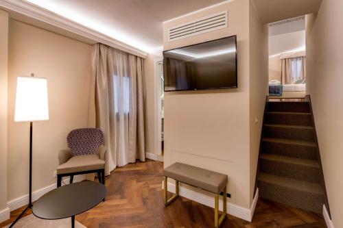 a room with a staircase with a television and a chair at BW Premier Collection CHC Continental in Venice