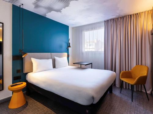 マルセイユにあるIbis Marseille Centre Prefectureの大きなベッドと黄色い椅子が備わるホテルルームです。