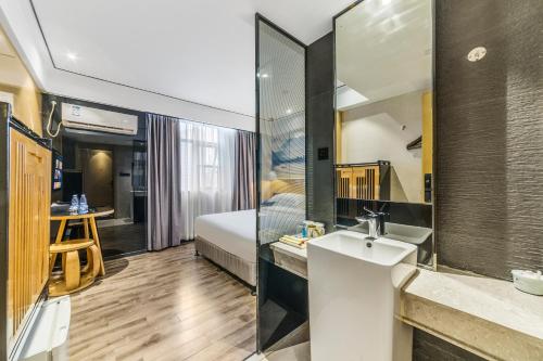 広州市にあるShangyuanHotel Quzhuang Branchの洗面台付きのバスルームと寝室