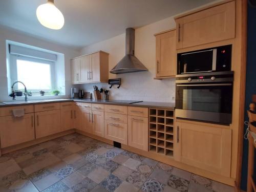 a kitchen with wooden cabinets and a stove top oven at Gîte Le Petit Bacchus in Sainte-Croix-Hague