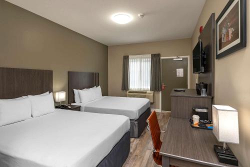 a hotel room with two beds and a desk at Econo Lodge in Prince George