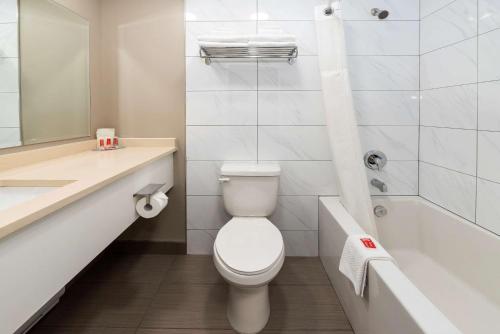 a bathroom with a toilet and a sink and a tub at Econo Lodge in Prince George
