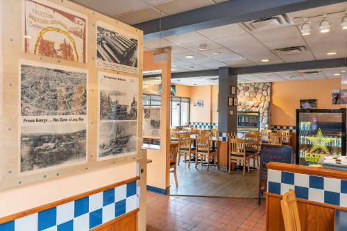 a restaurant with tables and chairs and posters on the walls at Econo Lodge in Prince George