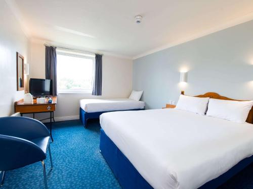 una camera d'albergo con due letti e una televisione di ibis budget Glasgow Cumbernauld a Glasgow