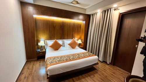 a bedroom with a large bed with a wooden headboard at IP Royal Hotel - New Delhi in New Delhi