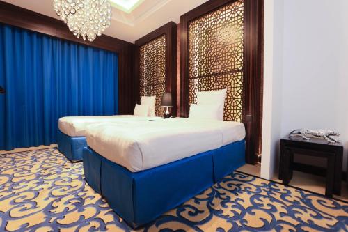 a hotel room with two beds and a chandelier at Nordic Palace and spa in Manama