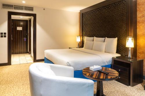 a hotel room with a bed and a table and a chair at Nordic Palace and spa in Manama