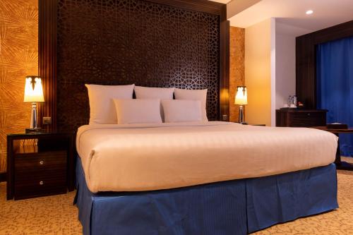 a large bed with white pillows in a hotel room at Nordic Palace and spa in Manama