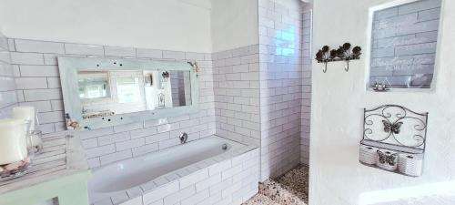 a white bathroom with a tub and a mirror at Casa Pescador Beach House in Struisbaai