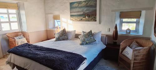 a bedroom with a bed and two chairs at Casa Pescador Beach House in Struisbaai