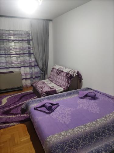 a bedroom with a purple bed and a chair at Apartments Milijana in Soko Banja