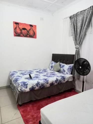 a bedroom with a bed and a picture on the wall at Linze lodge in Durban