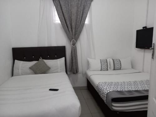 a small bedroom with two beds and a tv at Linze lodge in Durban