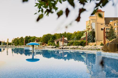 a swimming pool with a blue umbrella in the water at SunGarden Golf & Spa Resort in Cluj-Napoca