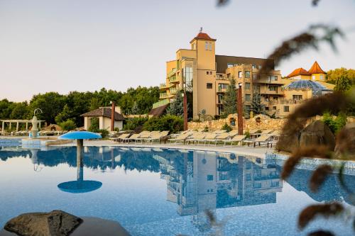 a swimming pool with a blue umbrella in front of a building at SunGarden Golf & Spa Resort in Cluj-Napoca