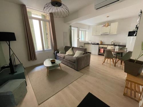 a living room with a couch and a table at L’olivier - Appartement in Paulhan