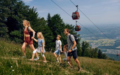 a family walking on a hill with a gondola at Pohorje Village Wellbeing Resort - Forest Apartments Videc in Pohorje