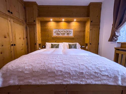a bedroom with a large white bed with wooden walls at Hotel da Beppe Sello in Cortina dʼAmpezzo