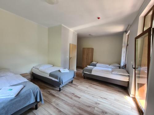three beds in a room with wooden floors at Willa Góralka in Miedzygorze
