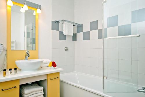 ein Badezimmer mit einem Waschbecken, einer Badewanne und einer Dusche in der Unterkunft Residhome Genève Prévessin Le Carré d'Or in Prévessin-Moëns