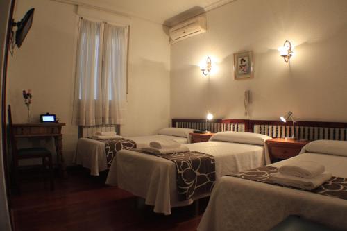 a group of four beds in a room at Hostal Esmeralda in Madrid