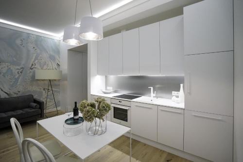 a kitchen with white cabinets and a table with plants on it at Błękitny Apartament in Grodzisk Mazowiecki