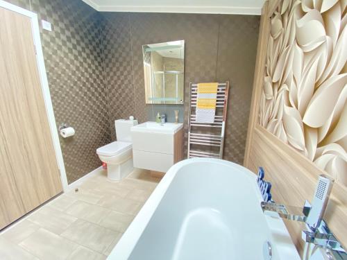 a bathroom with a tub and a toilet and a sink at Spring Lodge in South Cerney