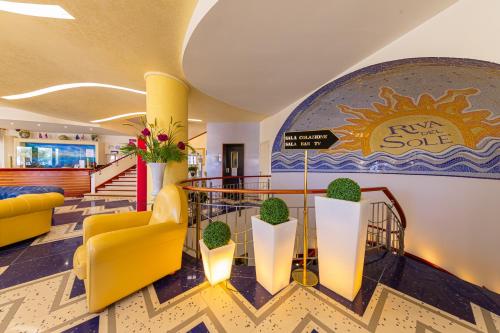 a lobby with yellow and white furniture and aire sale sign at Hotel Riva Del Sole in Cefalù