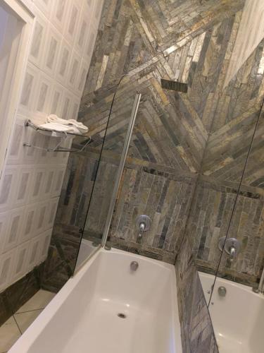 a bathroom with a glass ceiling and a tub at Obaa Sima Guest House in Mthatha