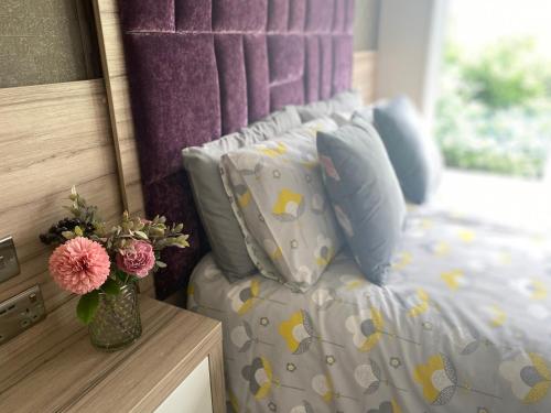 a bed with pillows and a vase with flowers on it at Spring Lodge in South Cerney