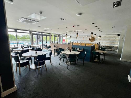 a dining room with tables and chairs and windows at Spring Lodge in South Cerney