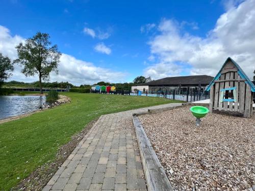 a small house next to a body of water at Spring Lodge in South Cerney