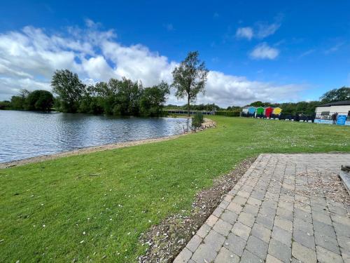 a grassy field next to a body of water at Spring Lodge in South Cerney