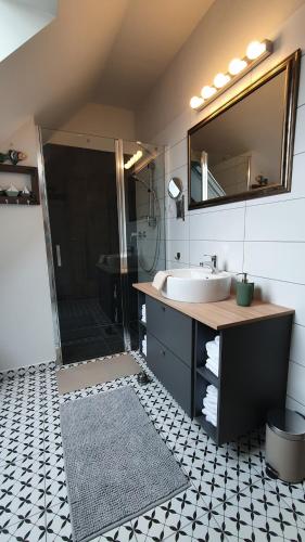 a bathroom with a sink and a shower with a mirror at Relax Balaton Apartmanok in Balatonfüred