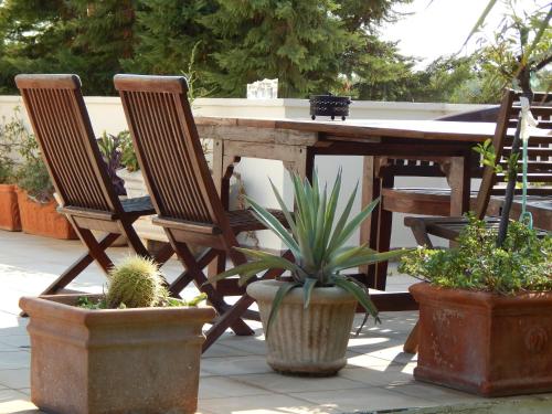 a wooden table with chairs and potted plants on a patio at Villa Vravrona Tower & Suites in Markopoulo