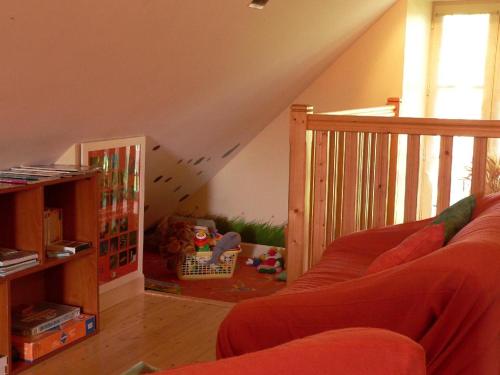 a living room with a red couch and a staircase at Maison d'Hôtes La Nichée in Rochefort-Montagne