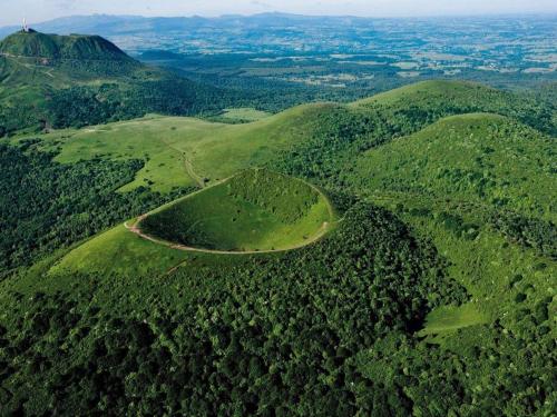 an aerial view of a mountain with trees and a road at Maison d'Hôtes La Nichée in Rochefort-Montagne