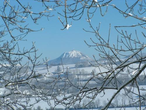 a mountain in the distance with snow covered trees at Maison d'Hôtes La Nichée in Rochefort-Montagne