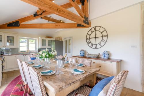 a kitchen with a table with chairs and a clock on the wall at Ivy Cottage in Chippenham