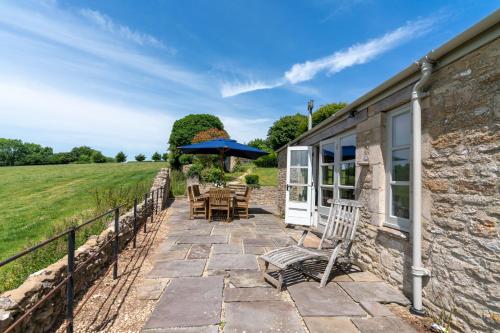 un patio con sillas y una sombrilla junto a un edificio en Ivy Cottage en Chippenham