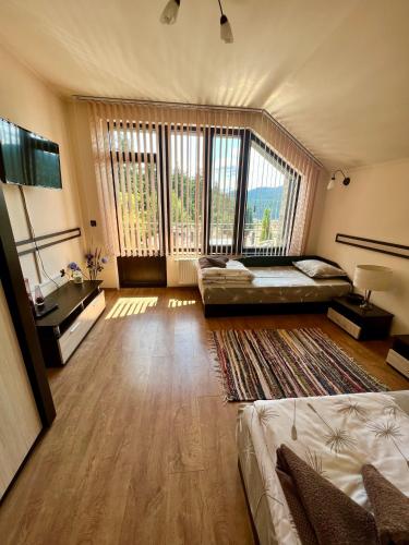 a large room with two beds and a large window at Rodopski Ailyak in Dospat