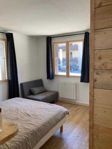 a bedroom with a bed and a chair and a window at Le très grand Appart in Uvernet